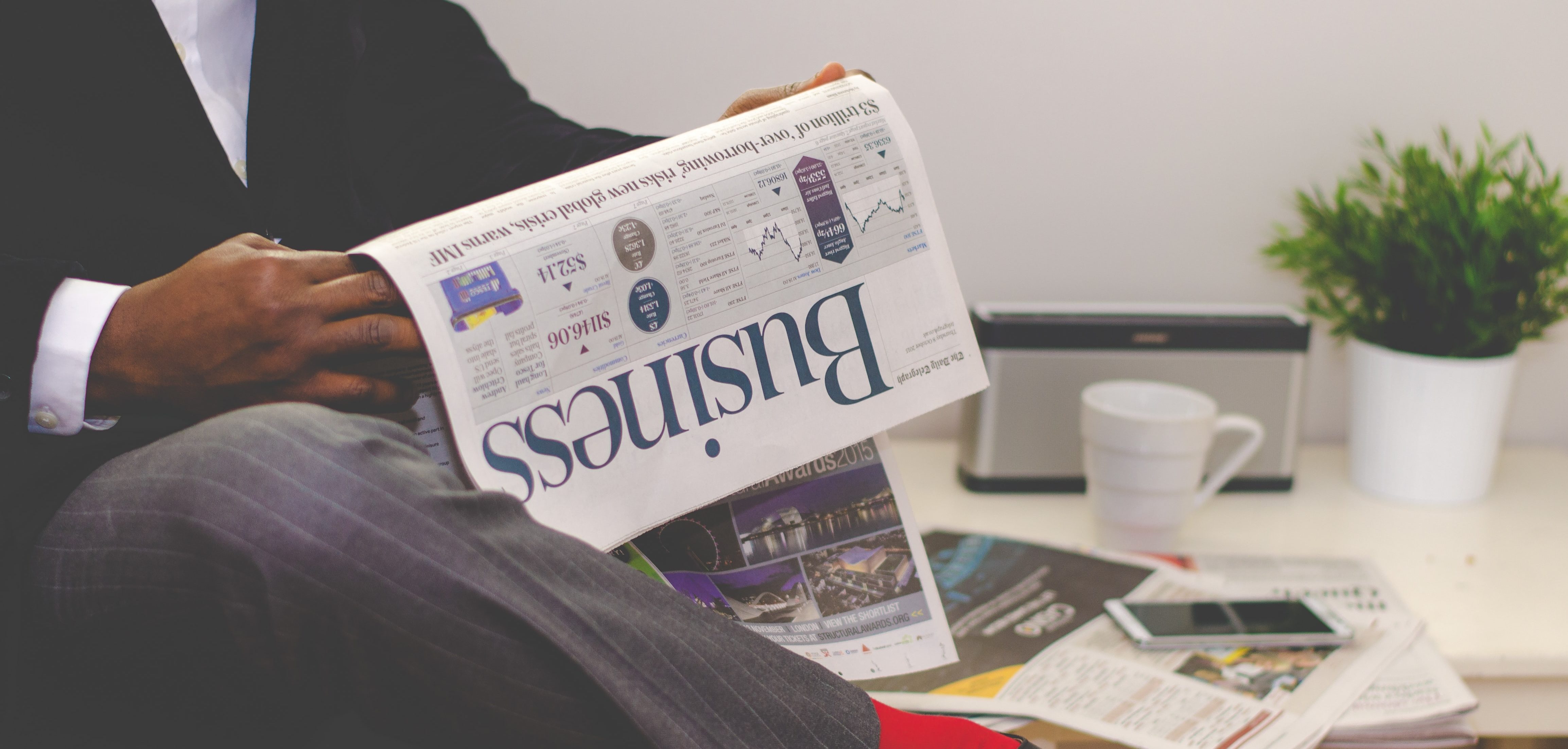 A man in a suit sits reading the business section of a newspaper